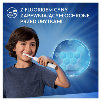 Uśmiechnięty chłopiec myje zęby Oral-B Junior, z tekstem o fluorku cyny dla ochrony przed ubytkami na błękitnym tle.