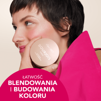 Uśmiechnięta kobieta prezentuje okrągły rozświetlacz Bourjois Maxi Round Pot, zapewniający łatwe blendowanie i blask.