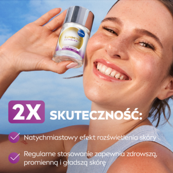 Uśmiechnięta kobieta z piegami trzyma Luminous630 Esencję, z tekstem o jej 2X skuteczności rozświetlania skóry.