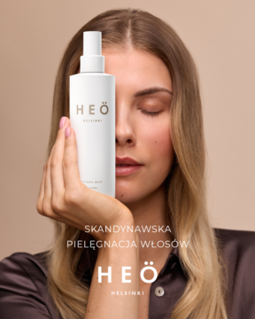 Mgiełka nawilżająca Heö Hydra Mist w białej butelce, trzymana przez kobietę; ułatwia rozczesywanie włosów suchych i farbowanych.
