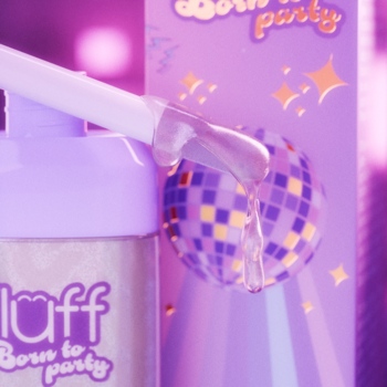 Fioletowy błyszczyk Fluff Born to Party z aplikatorem, obok brokatowa kula dyskotekowa na pudełku.