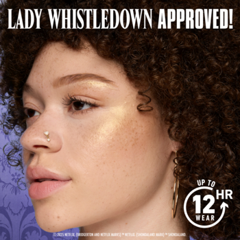 Kobieta z błyszczącym, złotym rozświetlaczem Lady Whistledown Approved na policzkach, makijaż do 12h.
