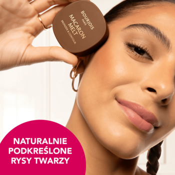 Kobieta z uśmiechem trzyma brązowy bronzer Bourjois Macaron Melt przy policzku, kremowo-pudrowa formuła.