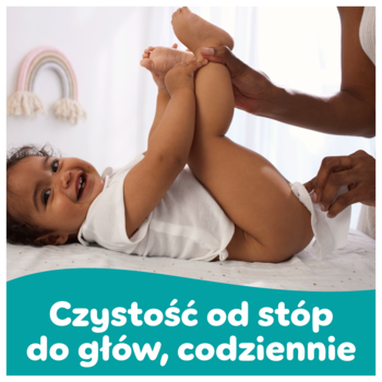 Uśmiechnięte dziecko leży na przewijaku, dorosły zmienia pieluszkę. Chusteczki Pampers Fresh & Clean dla delikatnej pielęgnacji.