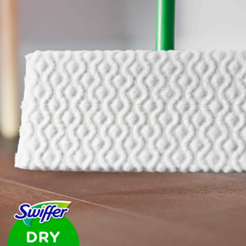Biały, teksturowany wkład Swiffer Dry do mopa na drewnianej podłodze, zbliżenie z widocznym kijem.