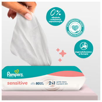 Pampers Sensitive chusteczki nawilżane. Dłoń wyciąga białą chusteczkę z opakowania. Widoczne: 0% alkoholu, bez zapachu.