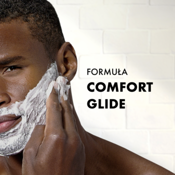 Mężczyzna w trakcie golenia, nakłada piankę Gillette Classic Comfort Glide na twarz. Widoczny tekst: FORMULA COMFORT GLIDE.