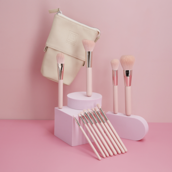 Zestaw pędzli Ilū Basic z różowymi rączkami i srebrnymi skuwkami, na różowym tle, z beżowym etui.