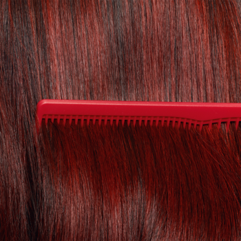 Czerwony grzebień delikatnie przeczesuje lśniące, intensywnie czerwone włosy. Wella Invigo Color Brilliance odżywka.