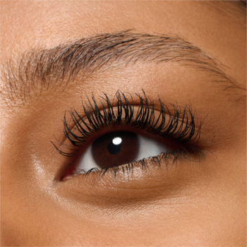 Zbliżenie na ciemnobrązowe oko z długimi, pogrubionymi rzęsami, podkreślone tuszem. Naturalne brwi.