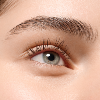 Zbliżenie na prawe oko kobiety z jasną tęczówką, długimi rzęsami i naturalną, gęstą brwią.