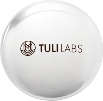 Highlighter Mini Glow TULI LABS, biały rozświetlacz w okrągłym, lśniącym opakowaniu z brązowym logo.