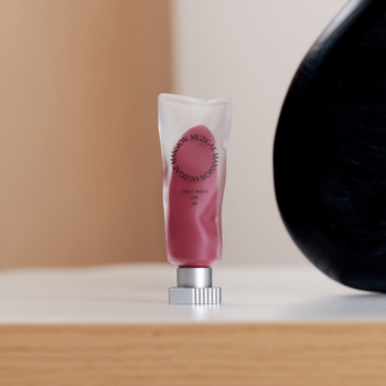 Muzigae Mansion matowy tint do ust Diva w różowo-czerwonej, przezroczystej tubce na jasnym tle, widok z przodu.