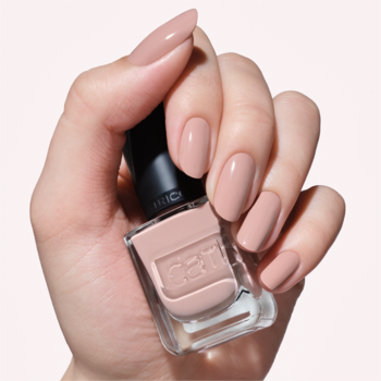 Ręka z beżowymi paznokciami o żelowym połysku, trzymająca lakier Catrice GEL AFFAIR 056 Naturally Yours nude.