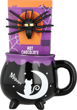 Czarny kubek-kociołek z białym kotem i księżycem, w nim fioletowe opakowanie 'HOT CHOCOLATE' z czarnym pająkiem.