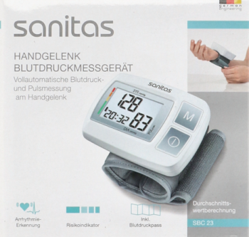 Sanitas: biały ciśnieniomierz nadgarstkowy z cyfrowym wyświetlaczem 128/83 mmHg, na tle opakowania.