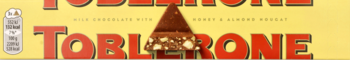 Toblerone: szwajcarska czekolada mleczna z nugatem miodowo-migdałowym. Żółte opakowanie, czerwony napis i czekolada.