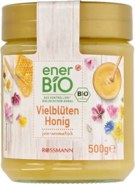 Szklany słoik miodu wielokwiatowego enerBiO Rossmann 500g, jasnożółty, z etykietą pełną barwnych kwiatów.