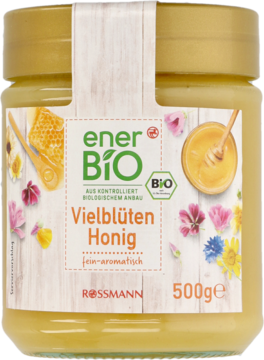 Szklany słoik miodu wielokwiatowego enerBiO Rossmann 500g, jasnożółty, z etykietą pełną barwnych kwiatów.