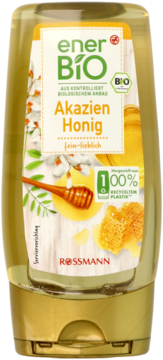 Miód akacjowy enerBiO w przezroczystej butelce z recyklingu, złota nakrętka, front. Etykieta z kwiatami akacji i miodem.