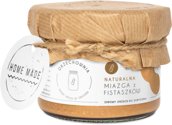Naturalna miazga z fistaszków 'Home Made' w szklanym słoiku, z papierową pokrywką i etykietą, widok z przodu.