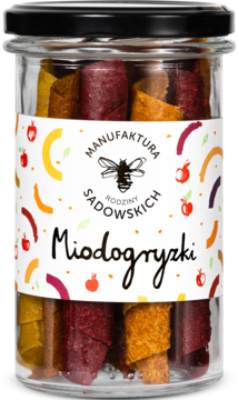 Słoik zdrowych Miodogryzków, owocowych ruloników w kolorach czerwonym, żółtym i pomarańczowym, z białą etykietą.