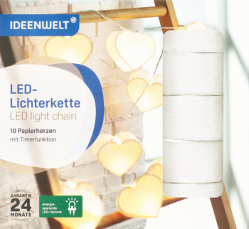 Opakowanie Ideenwelt LED-Lichterkette z 10 białymi papierowymi sercami, widoczne obok stosu białych ręczników.