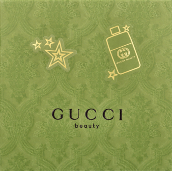 Zielona karta podarunkowa Gucci Beauty z wytłoczonym wzorem, złotym logo, gwiazdkami i ikoną perfum, idealna na prezent.