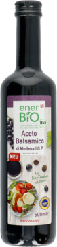 Ciemna butelka enerBiO Aceto Balsamico di Modena I.G.P., z etykietą i zdjęciem sałatki, widok z przodu.