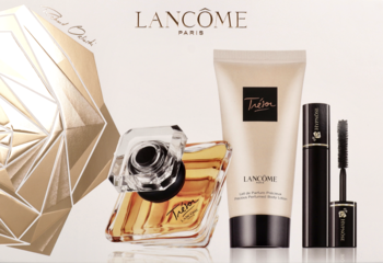 Zestaw Lancôme Trésor: złoty flakon EDP, beżowy balsam i czarny tusz, na tle z eleganckim złotym ornamentem.