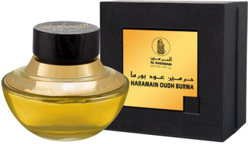 Złoty flakon Al Haramain Oudh Burma z czarną nakrętką, na tle czarnego pudełka z logo marki.