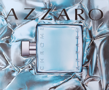 Męska woda toaletowa Azzaro Chrome w prostokątnej, jasnoniebieskiej butelce na srebrnym, pogniecionym tle.