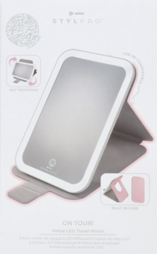Różowe lusterko LED STYLPRO On Tour Petite Travel Mirror, otwarte w stojaku, na białym pudełku.
