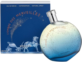 L'Ombre des Merveilles Hermes: okrągła butelka perfum z gradientem błękitu i brokatem, przed niebieskim pudełkiem.