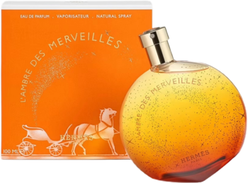 Hermes L'Ambre Des Merveilles woda perfumowana: kulista butelka z bursztynowym gradientem i brokatem, pomarańczowe pudełko z tyłu.