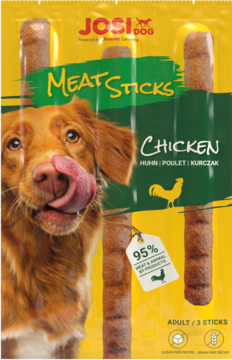JosiDog Meat Sticks Chicken, żółto-zielone opakowanie z psem liżącym się i trzema brązowymi pałeczkami, 95% mięsa.