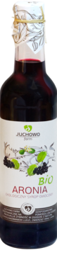 Wysoka butelka BIO syropu aroniowego Juchowo Farm, ciemne szkło, z etykietą przedstawiającą owoce. Widok z przodu.