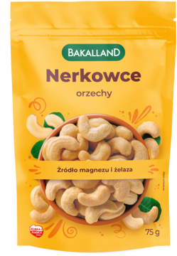 Żółte opakowanie Bakalland Nerkowce 75g, orzechy nerkowca w misce na tle zielonych liści, widok z przodu.