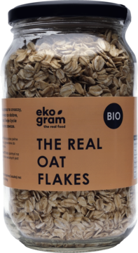 Płatki owsiane Ekogram BIO w szklanym słoiku z brązową etykietą 'THE REAL OAT FLAKES', widok z przodu.