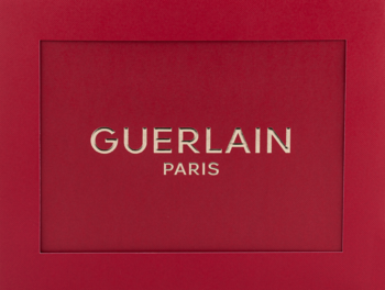 Czerwone, prostokątne pudełko zestawu Guerlain Habit Rouge z srebrnym logo GUERLAIN PARIS na środku, widok z przodu.
