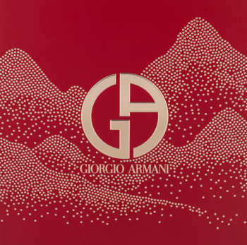 Czerwone pudełko prezentowe Giorgio Armani z logo GA i drobnymi złotymi kropkami tworzącymi wzory górskie.