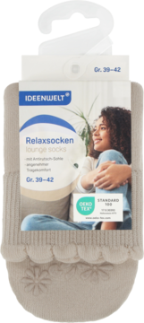 Beżowe skarpety Ideenwelt Relaxsocken (lounge socks) z kwiatowymi wypustkami antypoślizgowymi, w opakowaniu z kobietą na sofie.