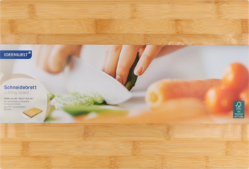 Bambusowa deska do krojenia z opakowaniem, na którym ręce kroją warzywa, widok z przodu.