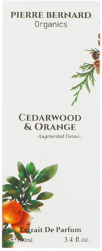 Białe pudełko Pierre Bernard Organics Cedarwood & Orange Extrait De Parfum, z gałązkami cedru i pomarańczy.