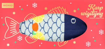 Dekoracyjny karp wigilijny, niebiesko-biała maskotka w łuski z cytrynowym wzorem, na czerwonym tle ze śnieżynkami.