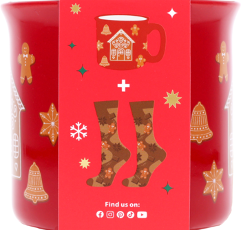 Czerwony kubek z wzorami pierników i dzwonków, zapakowany w zestaw ze skarpetkami gingerbread.