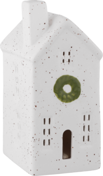 Biały ceramiczny domek dekoracyjny z cętkami, dwuspadowy dach, komin, zielony wianek i wycięte okna/drzwi.