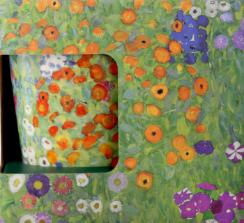 Kubek z motywem kwiatów w stylu Klimta, widoczny przez wycięcie w pudełku z takim samym wzorem. Dominują pomarańcze i zieleń.