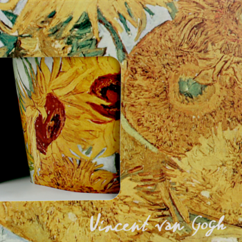 Kubek Vincent van Gogh ze słonecznikami, widoczny w wycięciu pudełka prezentowego, odcienie żółci i brązu.