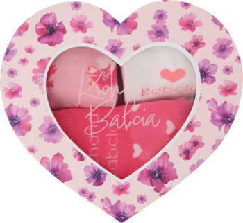 Różowe, sercowate pudełko prezentowe z kwiatowym wzorem, odsłaniające różowe tekstylia z napisem "Róża Babcia".
